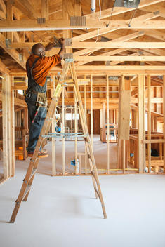 Black carpenter working on ceiling of unfinished room