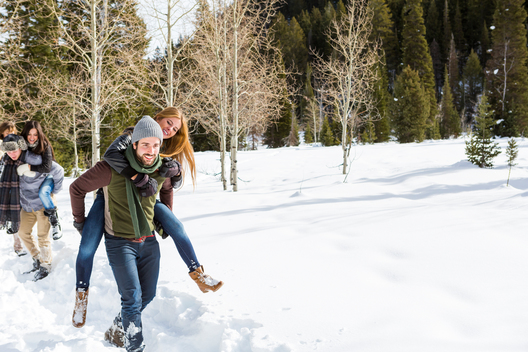 Couples piggyback riding on snow packed trail