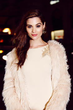 Closeup of model at night wearing a cream colored dress and fake fur jacket