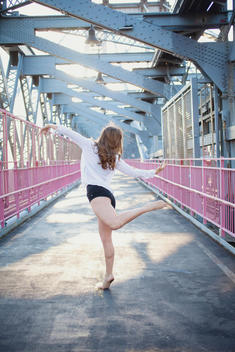 A young female dancer holding a dance pose on the Williamsburg bridge in New York City.
