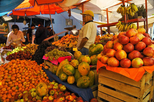 Man Selling Fresh Vegetables And Fruit At A Busy Village Market