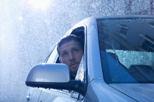 Businessman in car looking out window at rain