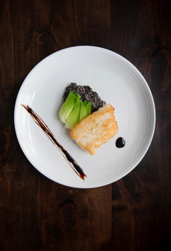 Chilean sea bass with beluga lentils, bacon, & bok choy shot from above.