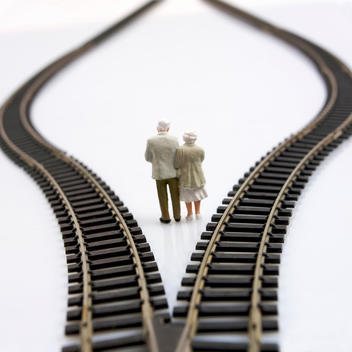 Model of elderly couple standing between two rail tracks