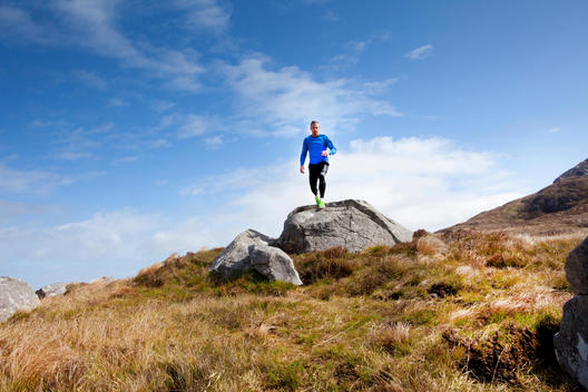 Young athletic man in peak action jumping from rock to rock in mountain