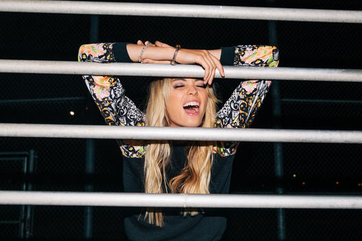 Girl yelling through bars of a set of bleachers at night.