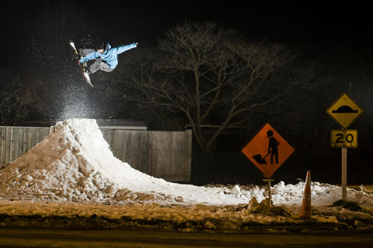 Snowboarder doing an air to fakie in the street at night