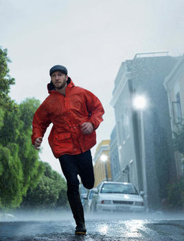 Man in raincoat running in rain