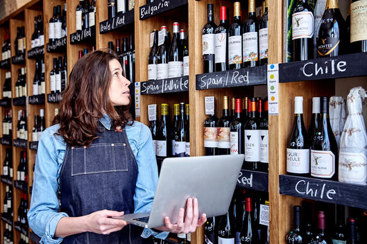 A small business owner checks her inventory with laptop in hand