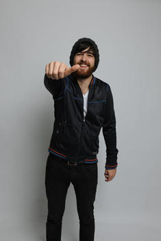 Smiling bearded male in his 20s, showing his thumb up at the camera