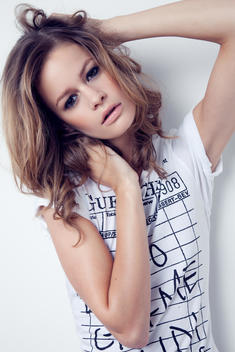 fashion model in studio, tilted head and posing with hands in hair, wearing a white t-shirt