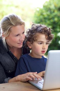 Mother showing her son (6-7) how to use laptop