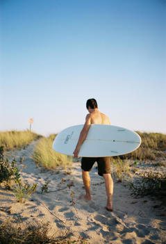 Young Man With Surfboard On Beach