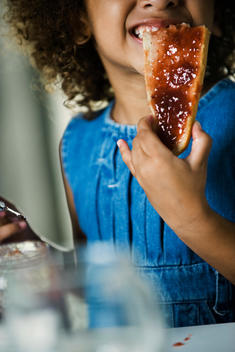 Little girl eating bread and jam, cropped