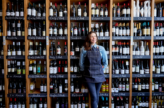 A small business owner stands for a portrait in her wine store