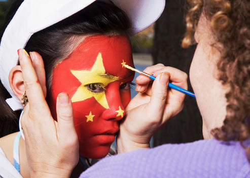 Woman painting Chinese flag on Chinese girl\'s face