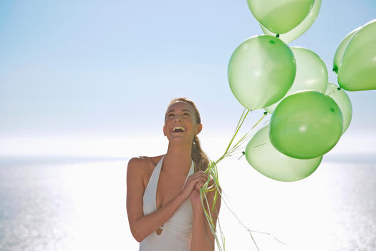 Close up of a woman holding a bundle of green balloons smiling