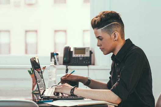 Creative business worker with an androgynous look working on her laptop