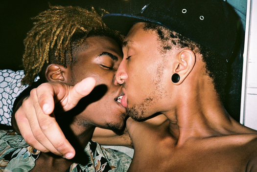 interior lifestyle shot of two African American men kissing each other, at night