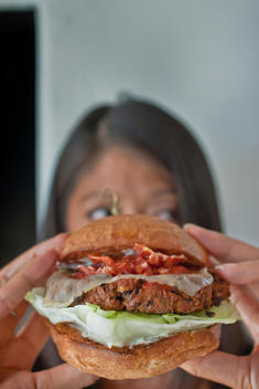 Woman Holding A Vegetarian Hamburger With Grilled Onions, Lettuce And Cheese