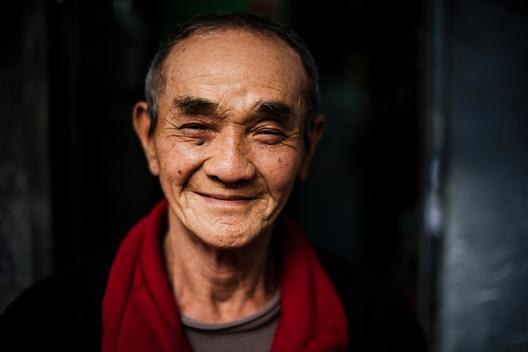Portrait of senior man wearing red scarf around neck looking at camera smiling