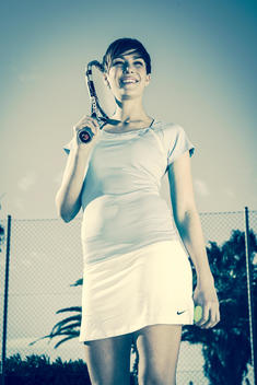 A girl wearing a tennis outfit walks onto the court