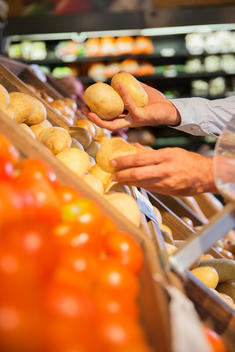 Close up of man selecting produce in grocery store