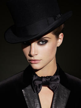 Young woman in black tuxedo and hat.