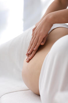Close up of massage therapist\'s hands massaging pregnant woman stomach