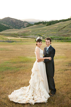 Bride and groom in vintage attire, in a field.