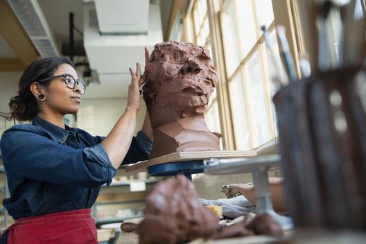 Artist sculpting face with clay in art studio