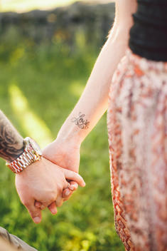 Couple Holding Hands with Love Tattoo