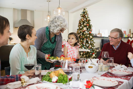 Grandmother serving food to family at Christmas dinner