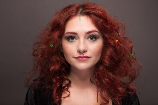 Portrait of young woman with curly red, fashion-forward hair and nose ring