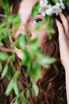 young woman hiding behind a tree
