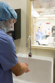 Caucasian surgeon washing hands in hospital sink