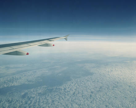 Flying Over The Clouds, The Wing Of The Airplane Leads On The Left Side Into The Image.