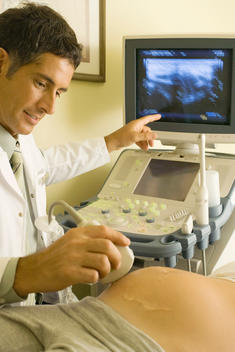 Doctor performing ultrasound on pregnant woman, cropped