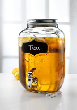Glass jar with tap dispenser containing fresh lemon tea drink