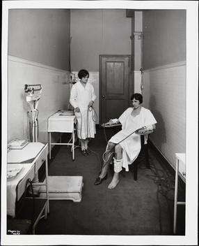 An Unidentified Woman Attached To A Medical Device By Her Arms And One Of Her Legs While A Nurse Looks On.