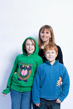 Portrait of caucasian mother, age 45-50 years old with son and daughter, ages 8-12 years old in studio
