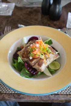 A dish with grilled fish and salad with lime on a table