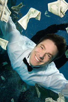 Man smiling under water with money