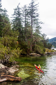 A kayaker paddles through the calm waters off the coast of Salt Spring Island, British Columbia, Canada.
