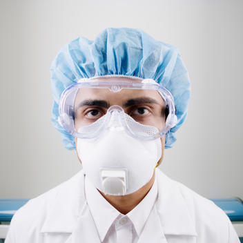 Portrait of male technician in protective gear and face mask in lab