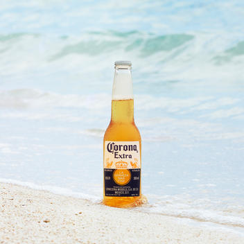A bottle of Corona is washed up on a white sand beach