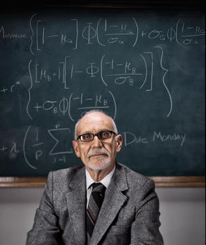 A teacher sitting in front of a blackboard.
