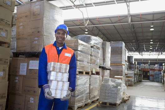 African worker carrying package in warehouse