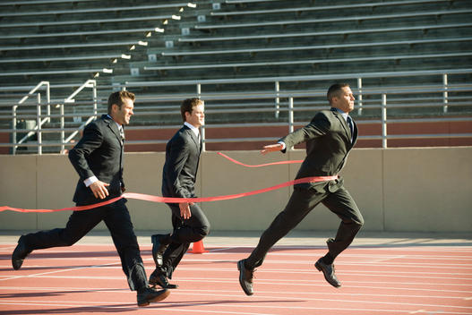 Businessman crossing finish line in race