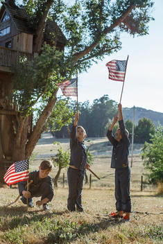 three boys holding up american flags